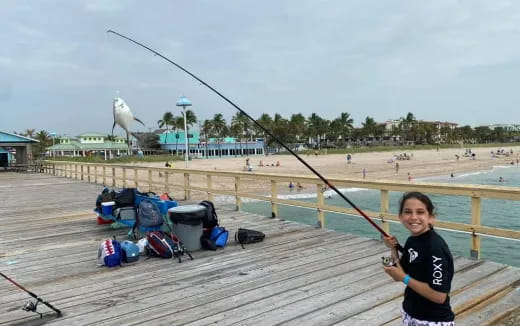 a boy holding a fishing pole on a pier