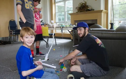 a person and a boy playing with toys in a room with other people