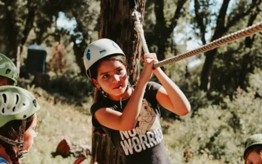 a young girl wearing a helmet and holding a bow and arrow