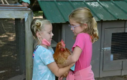 a couple of girls holding a chicken