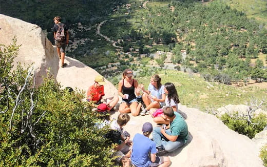 a group of people sitting on a rock ledge