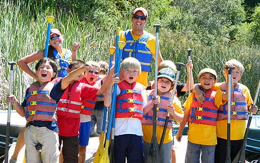 a group of people wearing life vests and holding poles