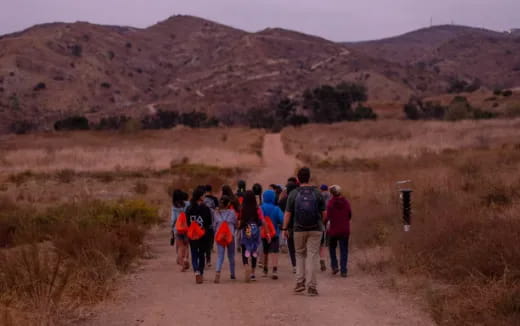 a group of people walking on a dirt road in the desert