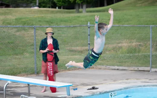 a boy jumping into a pool