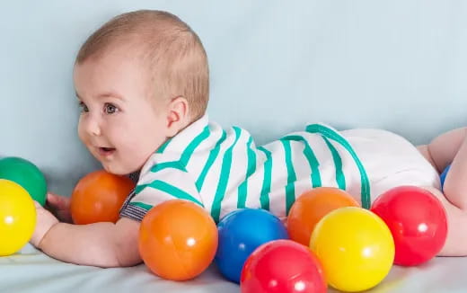 a baby lying on a blanket with colorful balls