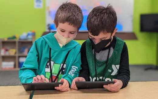 a couple of boys looking at a tablet