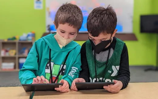 a couple of boys looking at a tablet