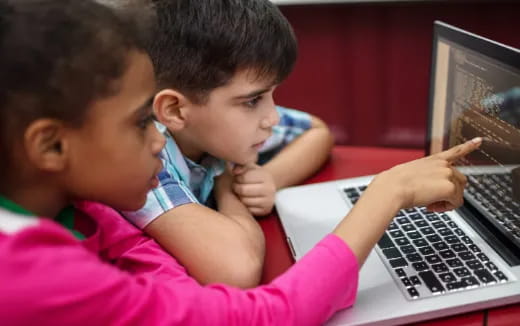 a couple of children looking at a laptop