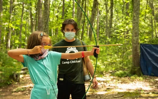 a couple of people wearing masks and holding bows and arrows