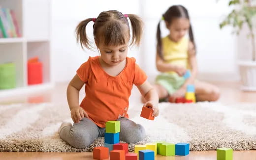 a couple of young girls playing with toys on the floor