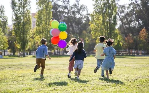 a group of children running with balloons