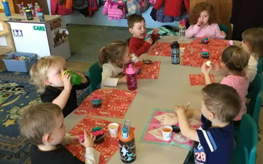 a group of children sitting around a table eating food
