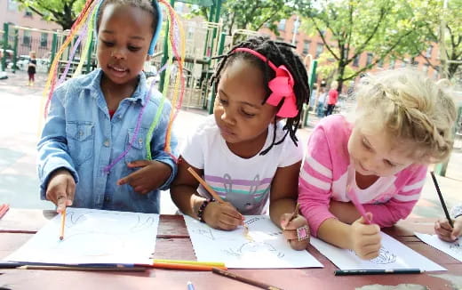 a group of children sitting at a table writing on paper