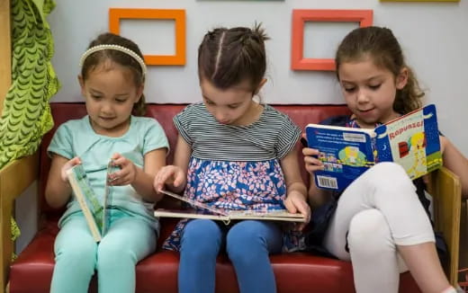 a group of children sitting on a couch reading books