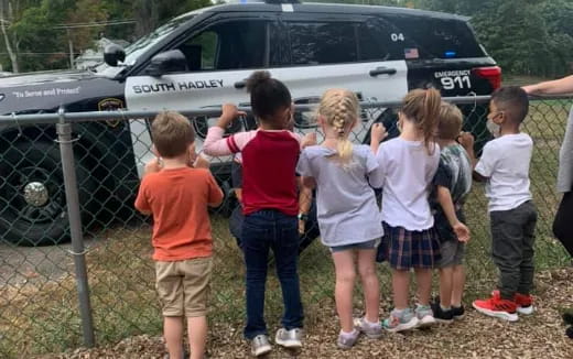 a group of children standing in front of a car