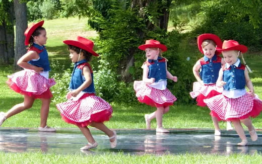 a group of children wearing red and blue dresses and hats