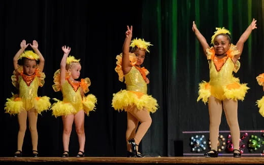 a group of girls in yellow dresses on a stage