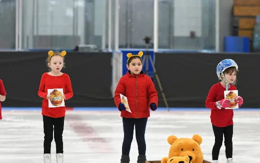 a group of kids wearing ice skates and holding cups