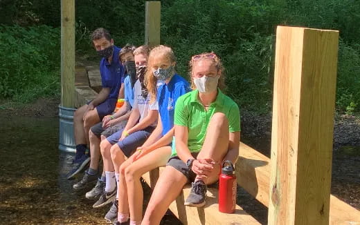 a group of people sitting on a bench with masks on