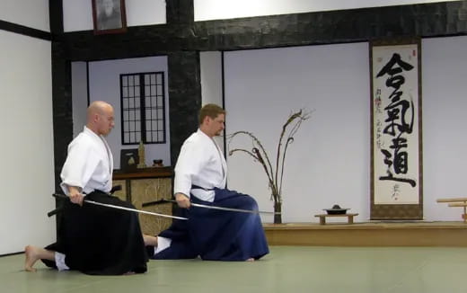 a man in a karate uniform sitting next to a man in a white shirt