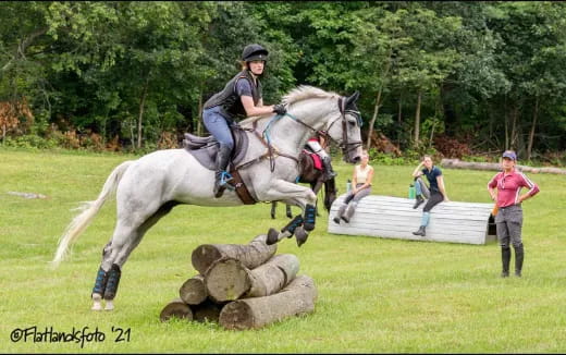 a man riding a horse over a log