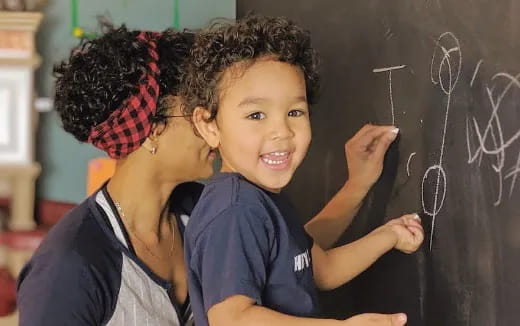 a person and a child writing on a blackboard