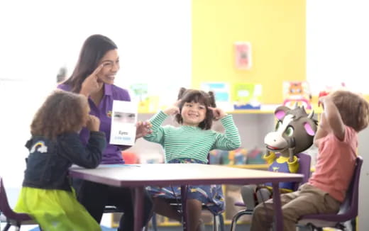 a person and children sitting at a table with a toy