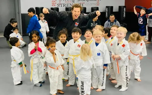 a person standing with a group of children in karate uniforms