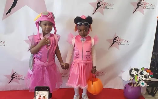 two girls wearing pink dresses and standing next to each other