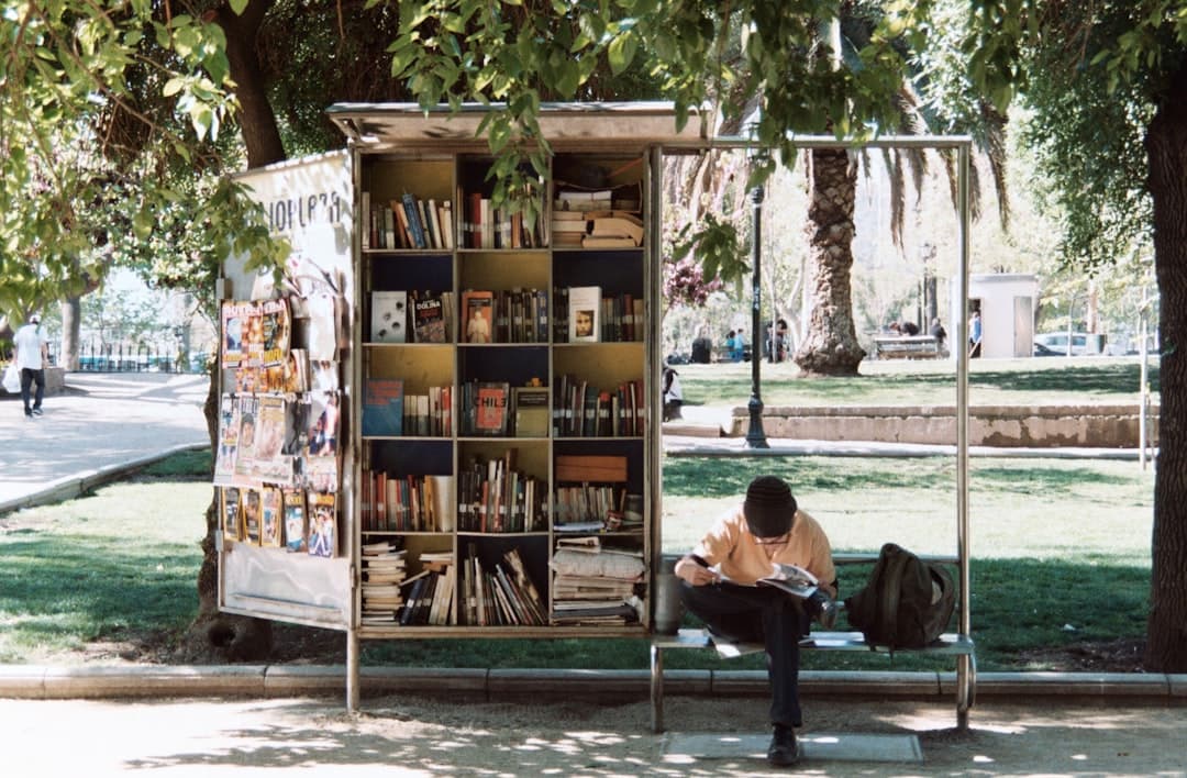 boy sitting on bench beside bookshelf