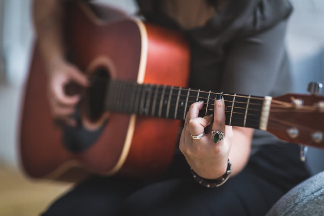 person sitting while using guitar