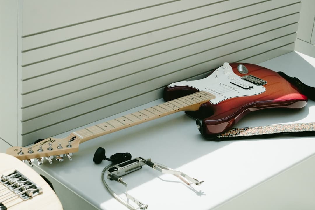 white and brown electric guitar on top of white wooden surface