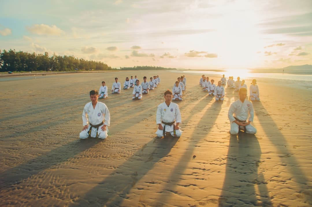 people kneeling on sandy ground