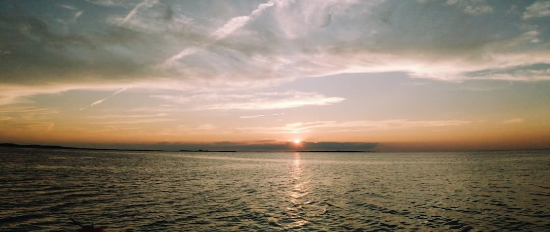 body of water under cloudy sky during sunset