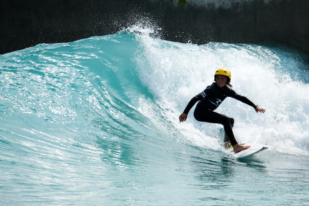 man in black wet suit riding yellow surfboard on water during daytime