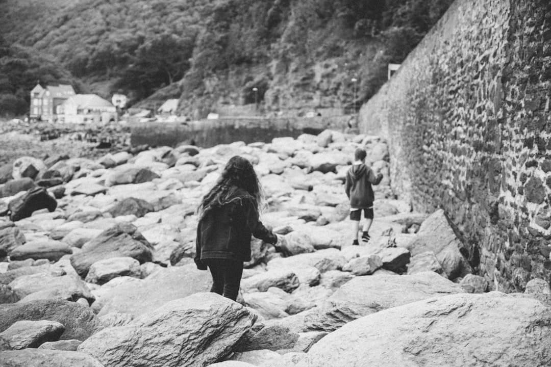 woman in black jacket walking on rocky shore