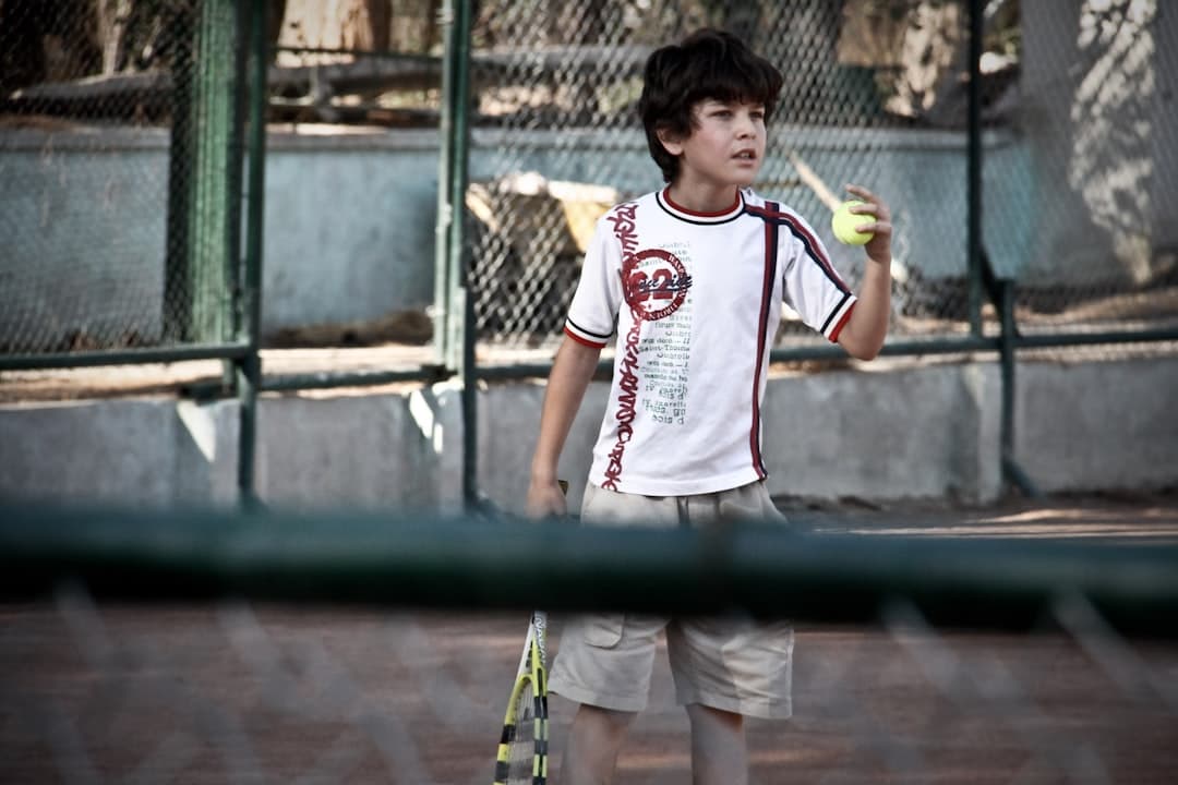 boy in white and red crew neck t-shirt holding yellow rope