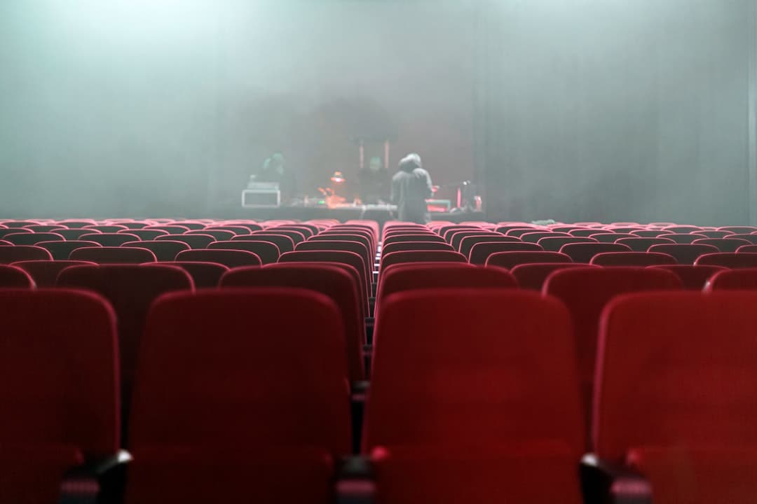 people sitting on red chairs watching a band performing on stage