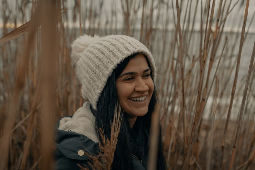 woman in white knit cap and black jacket smiling