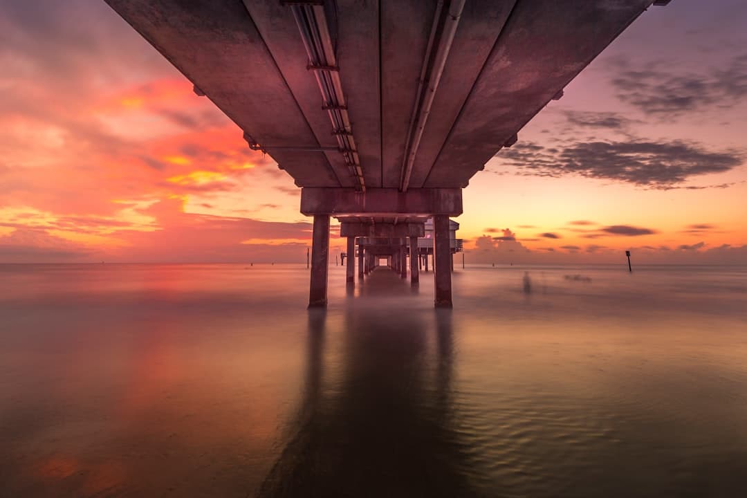 gray concrete bridge over the sea during sunset