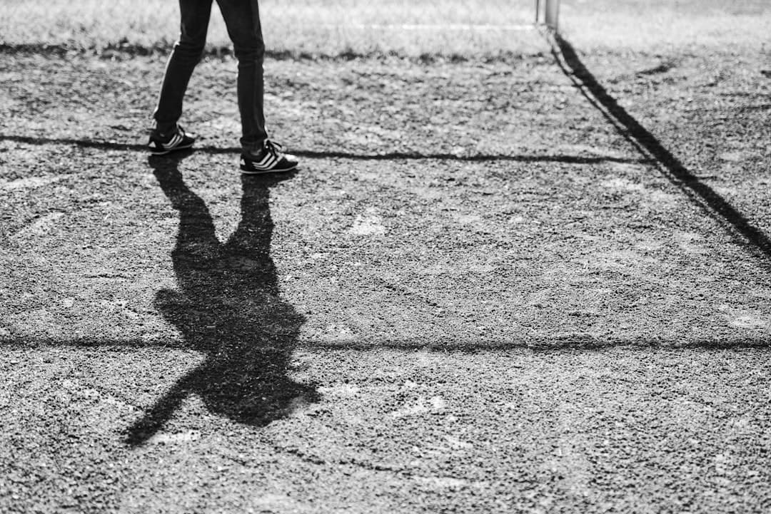 grayscale photo of person walking on field