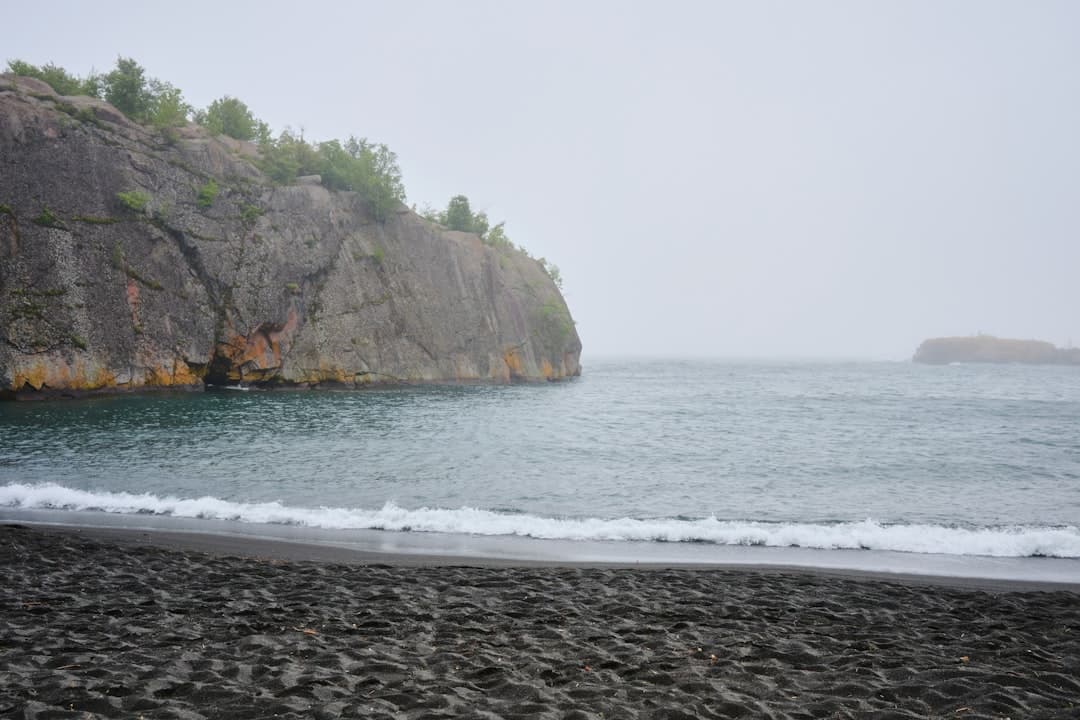 green and brown mountain beside sea during daytime