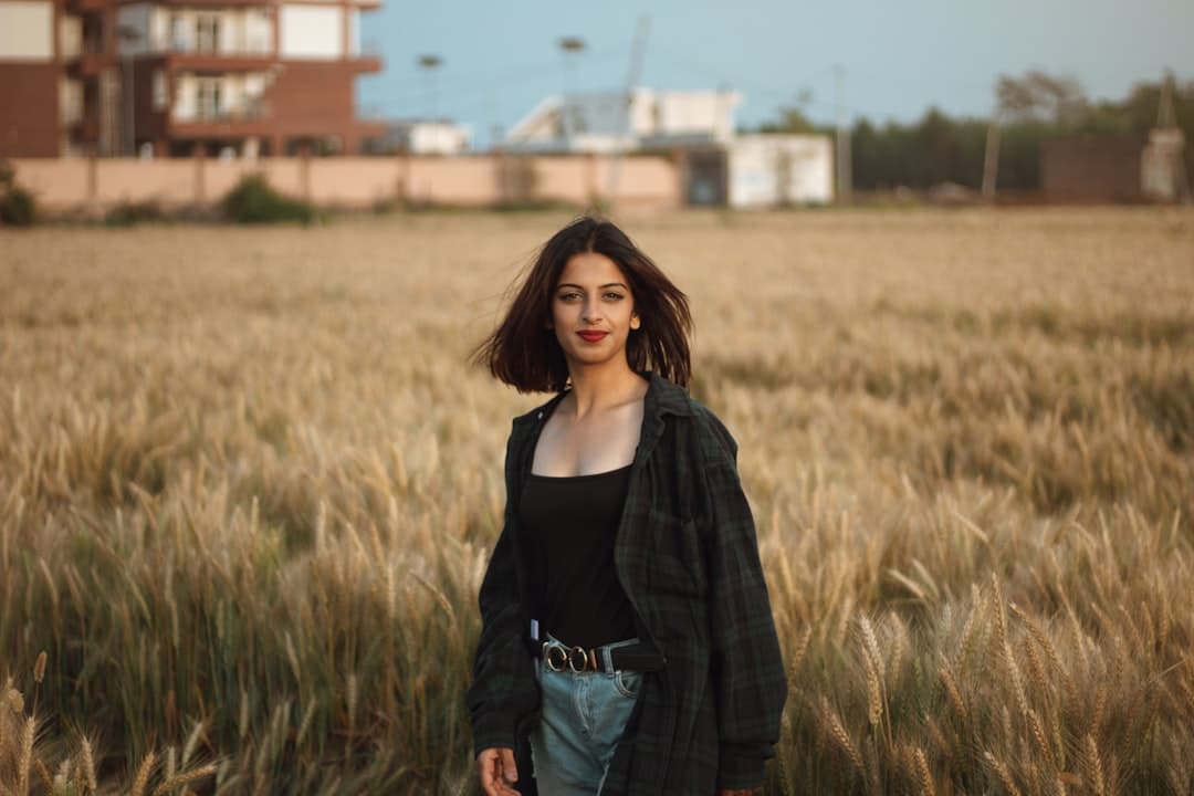 woman in black scoop neck shirt and blue denim jacket standing on brown grass field during