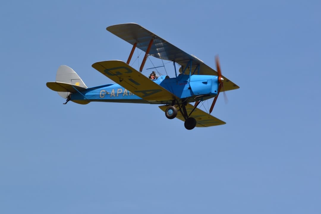 a small blue and yellow plane flying in the sky