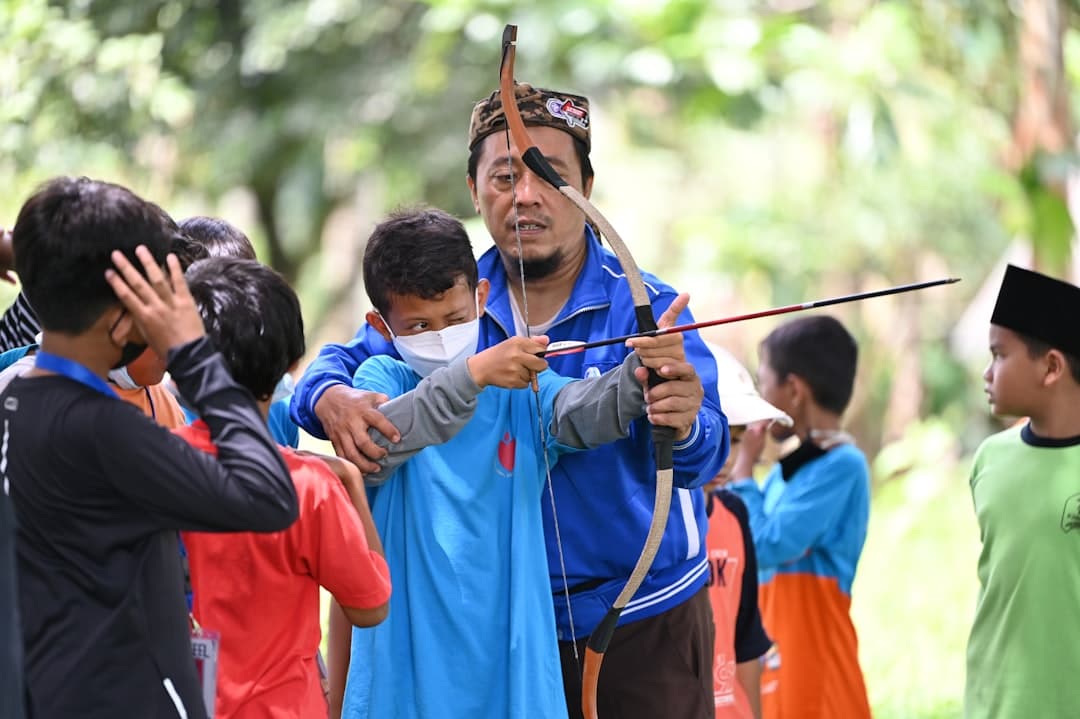 a man holding a bow and arrow in front of a group of people