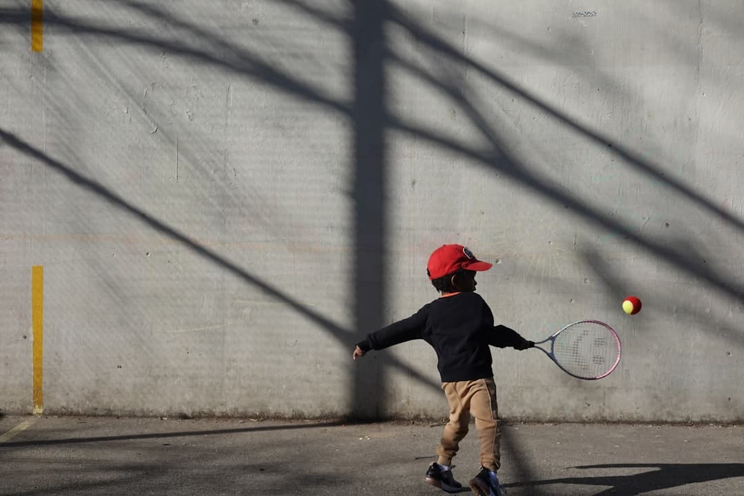 a young boy hitting a tennis ball with a racquet