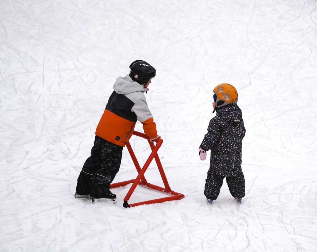 a couple of kids standing on top of a snow covered slope