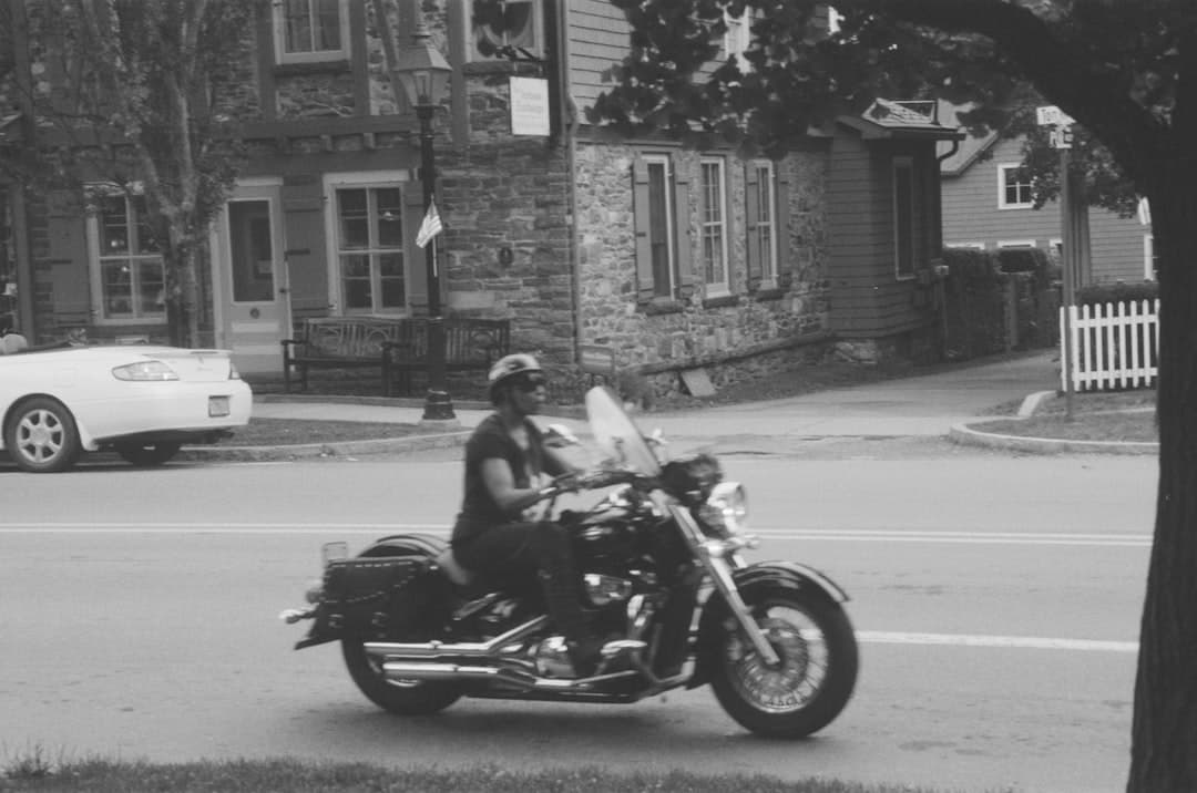 a man riding a motorcycle down a street next to a tree