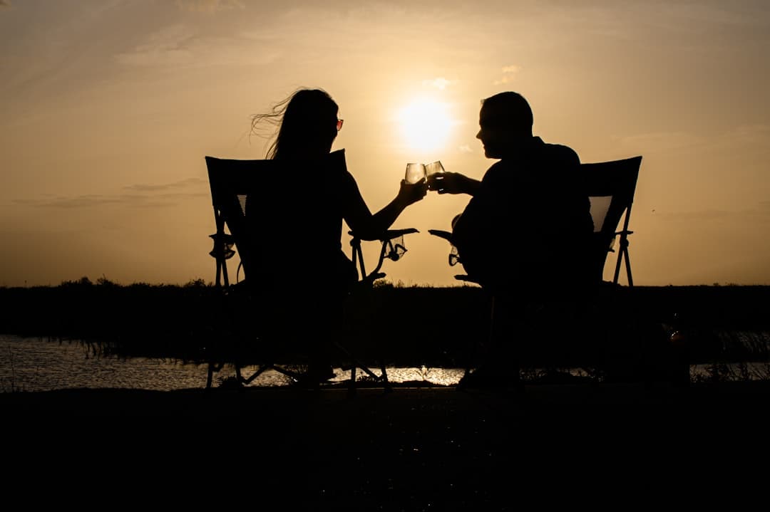 a man and woman sitting on a bench at sunset