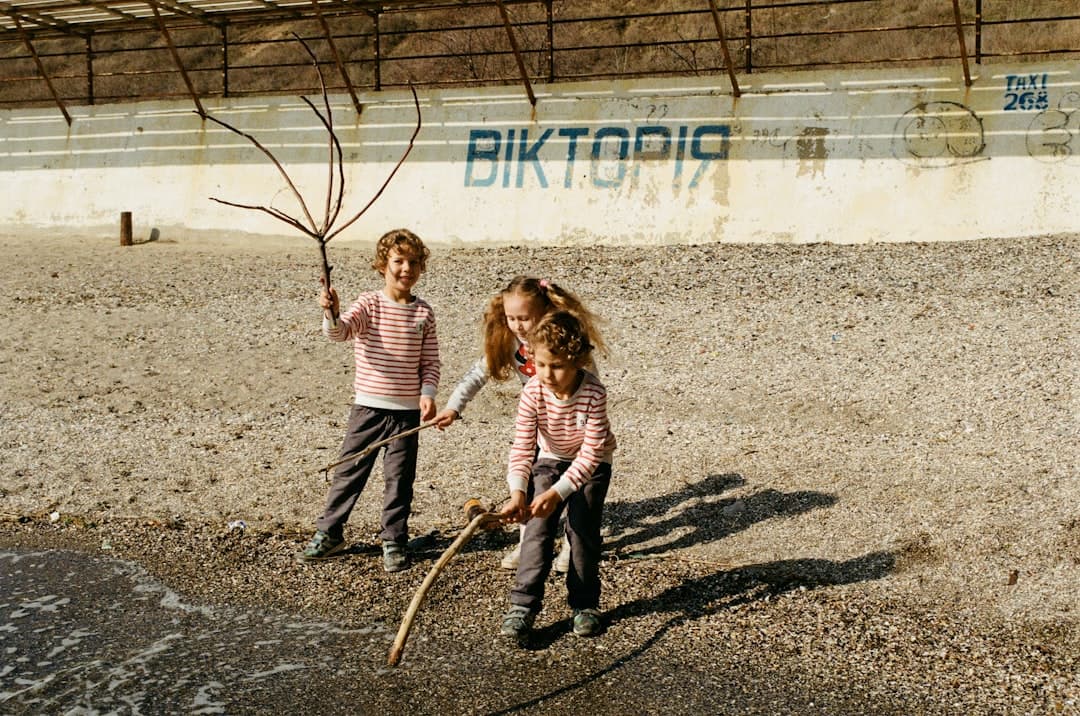 a couple of children playing with a tree in a dirt area